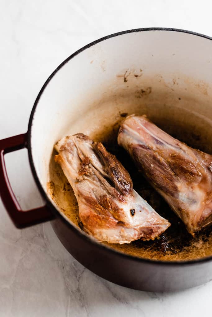 Uncooked lamb shanks in a pot