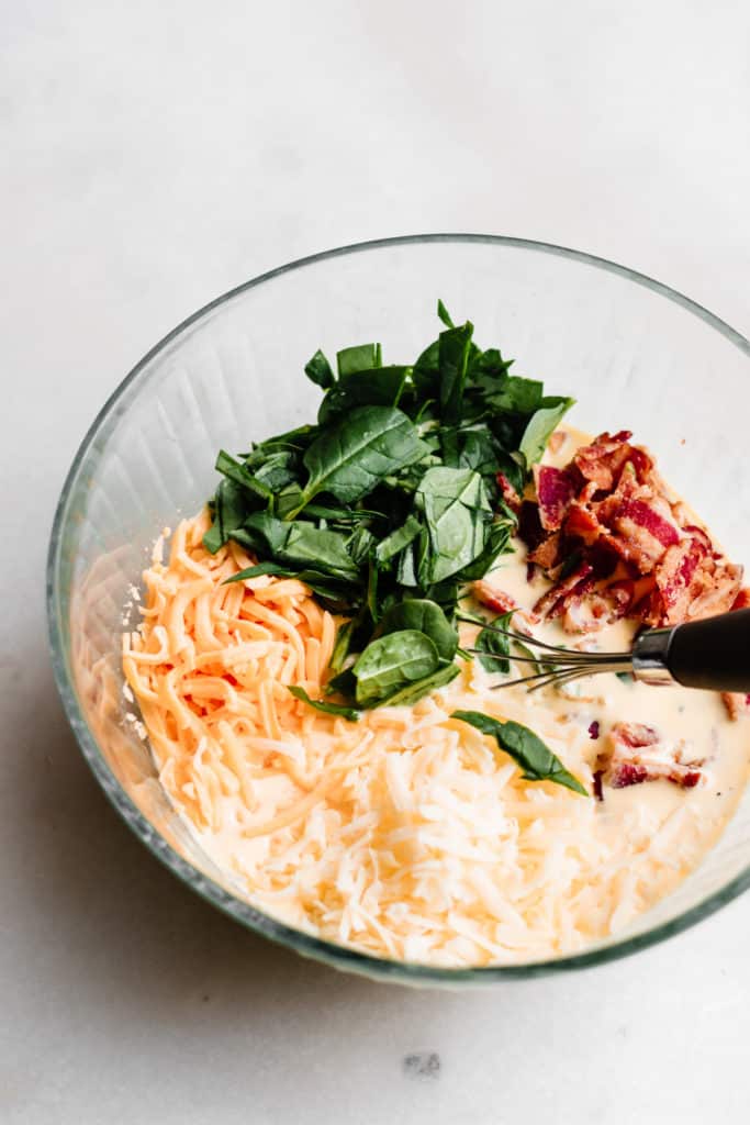 Cheese, spinach, milk, and bacon in a bowl