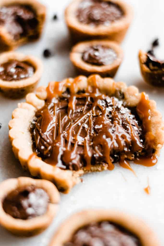 A close-up of mini cookie tart filled with nutella and drizzled with caramel.