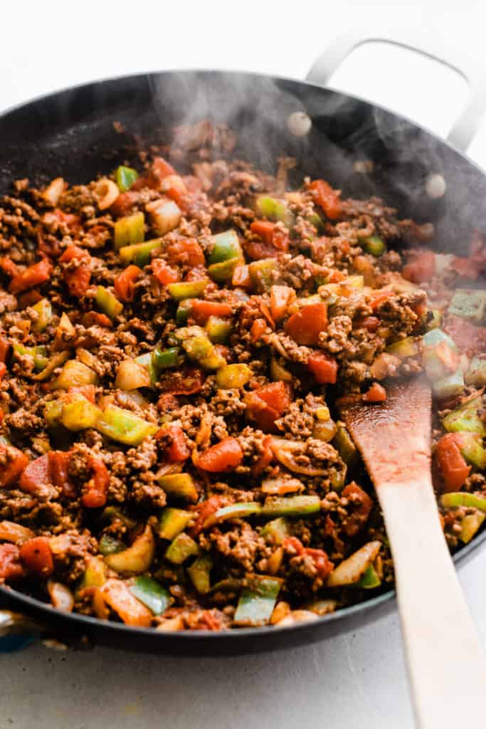 Beef and other ingredients sizzling in pan