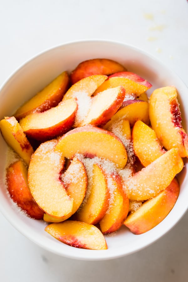 Sliced peaches and sugar in a bowl.