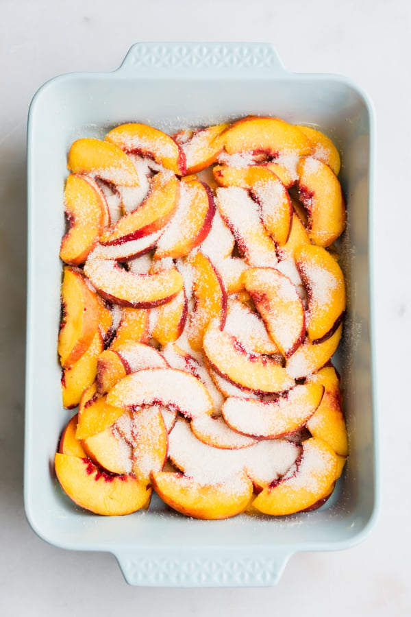 Sliced peaches and sugar in a pan.