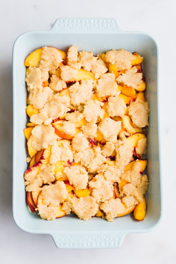 Sliced peaches and topping in a pan.