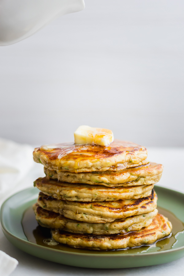 A stack of Zucchini Bread Pancakes with syrup.