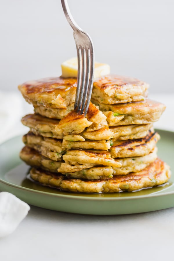 A stack of zucchini bread pancakes with syrup.