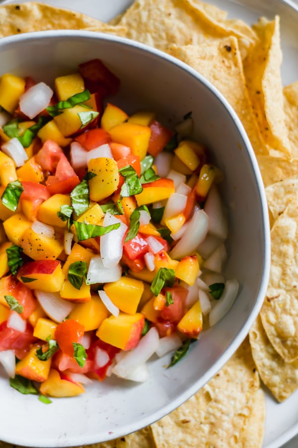 Peach salsa in a bowl and tortilla chips.