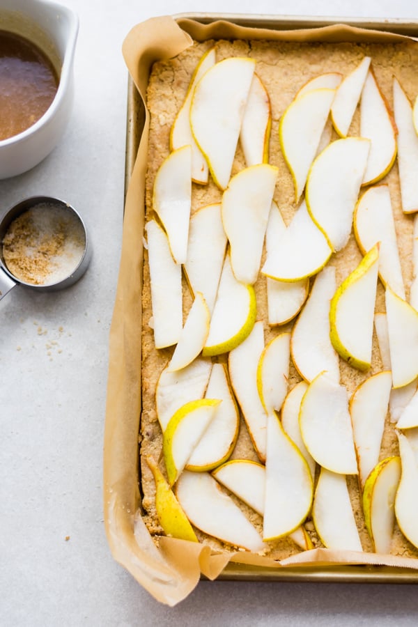 Sliced pears on dough in a tray.