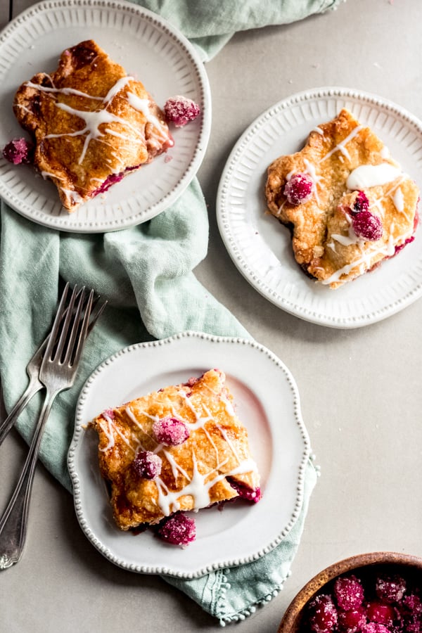 Squares of cranberry apple slab pie with maple glaze on plates.