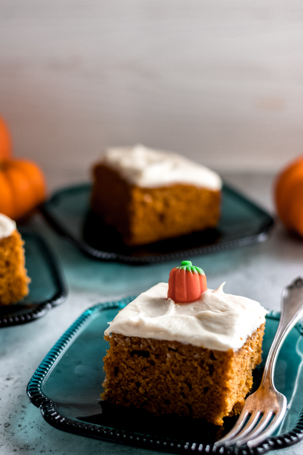 Slices of pumpkin spice cake with cream cheese frosting on plates.