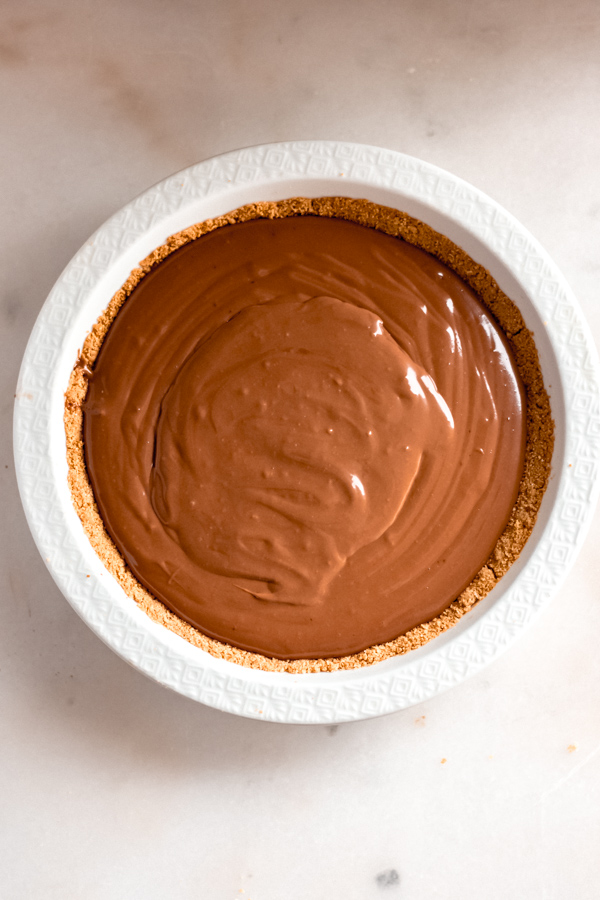 Chocolate cheesecake batter in a white pan.