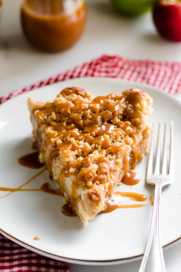 A slice of caramel drizzled caramel apple pie with homemade pie crust.