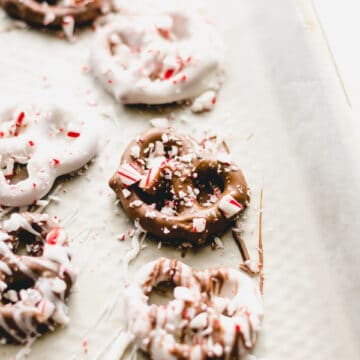 Chocolate dipped pretzels covered in crushed peppermint on a wax paper lined baking sheet.