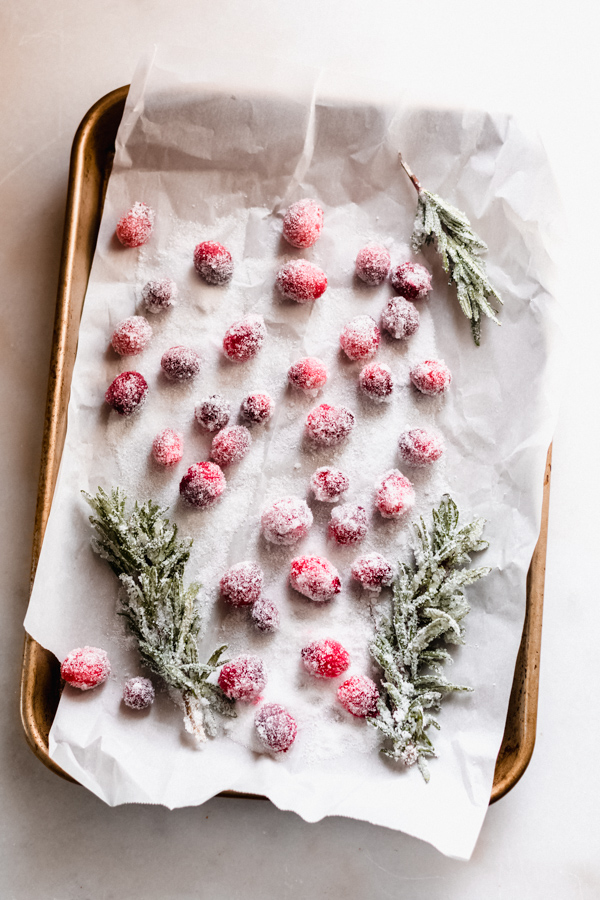 Sugared cranberries and rosemary trees on a baking tray.