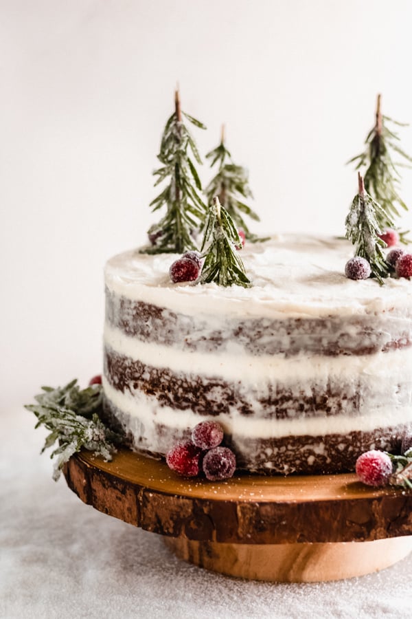 Gingerbread cake with mascarpone cream cheese frosting on a wooden cake stand.