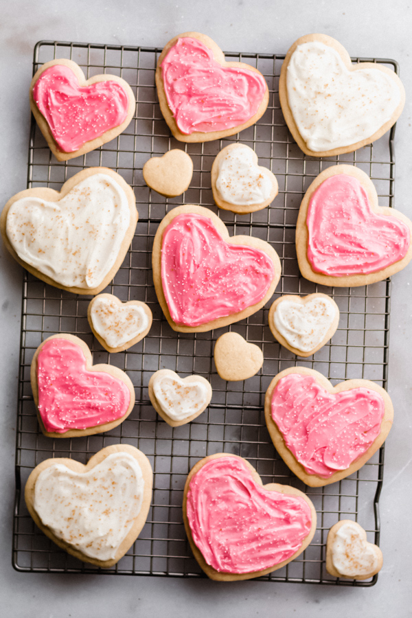 Frosted heart sugar cookies on a cooling rack.