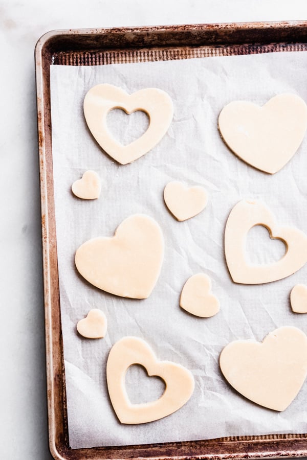 Cookie dough cut into hearts on a baking sheet, before being baked.