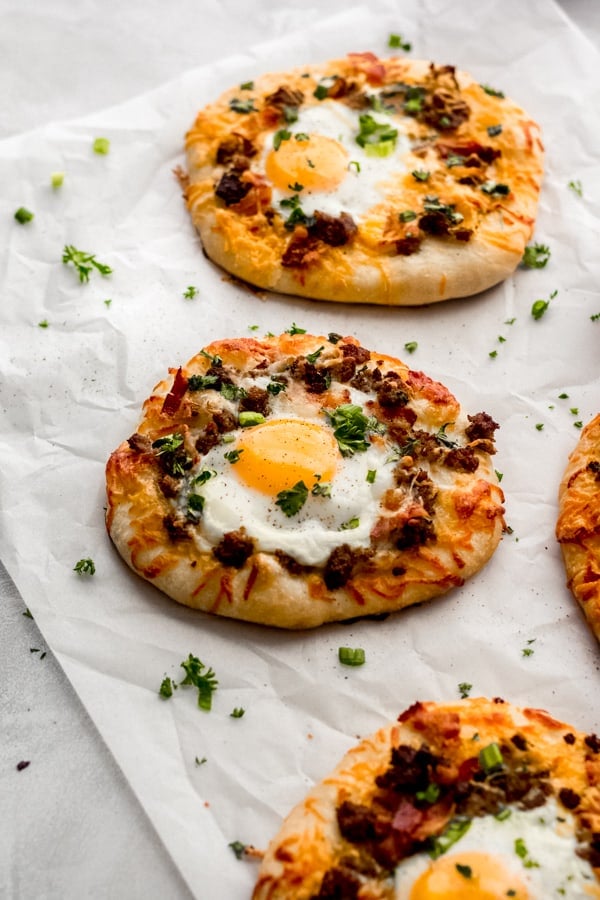 Breakfast pizzas on a white surface.