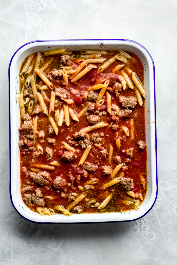 Tomato sauce, sausage, and pasta in a pan.