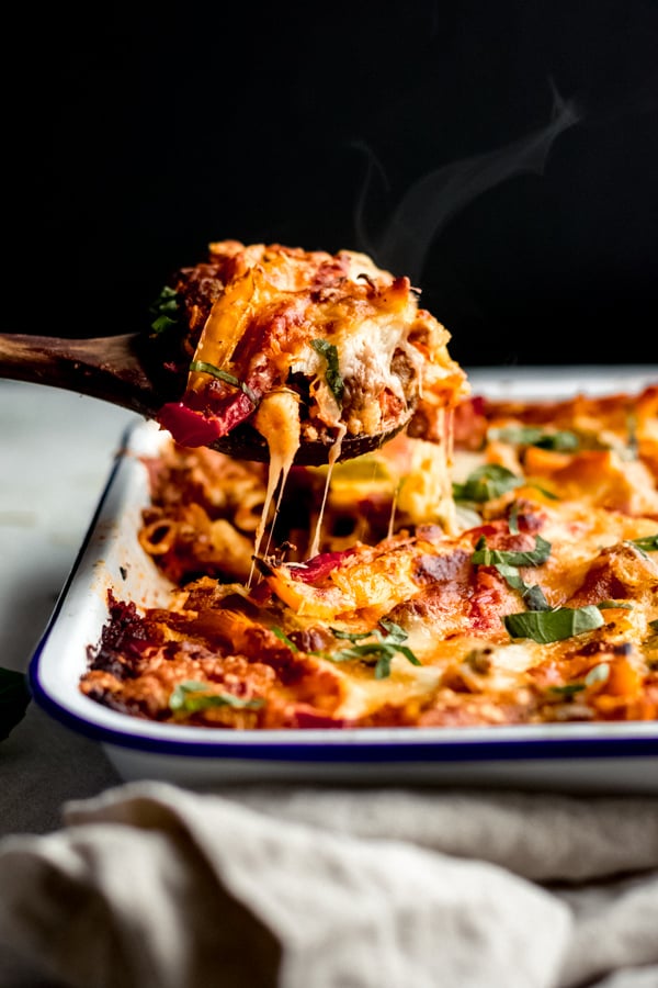 Cheesy pasta bake with sausage and peppers scooped up in a spoon.
