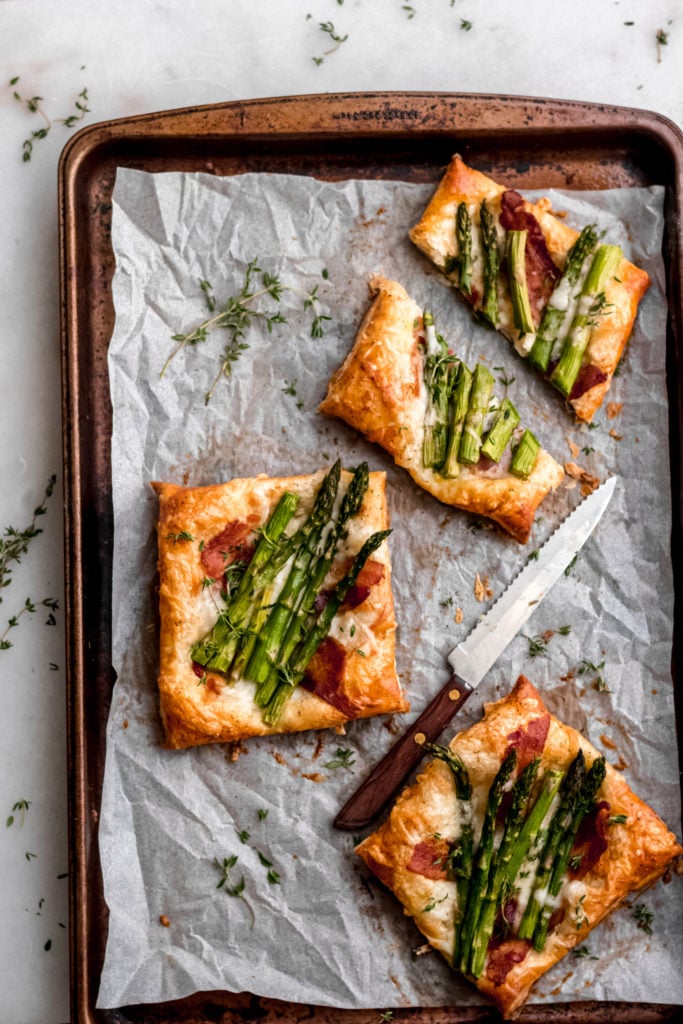 Asparagus tarts with bacon and gruyere on a baking tray.
