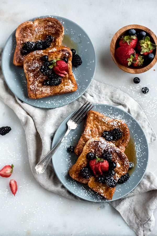 Brioche French toast on plates with berries.