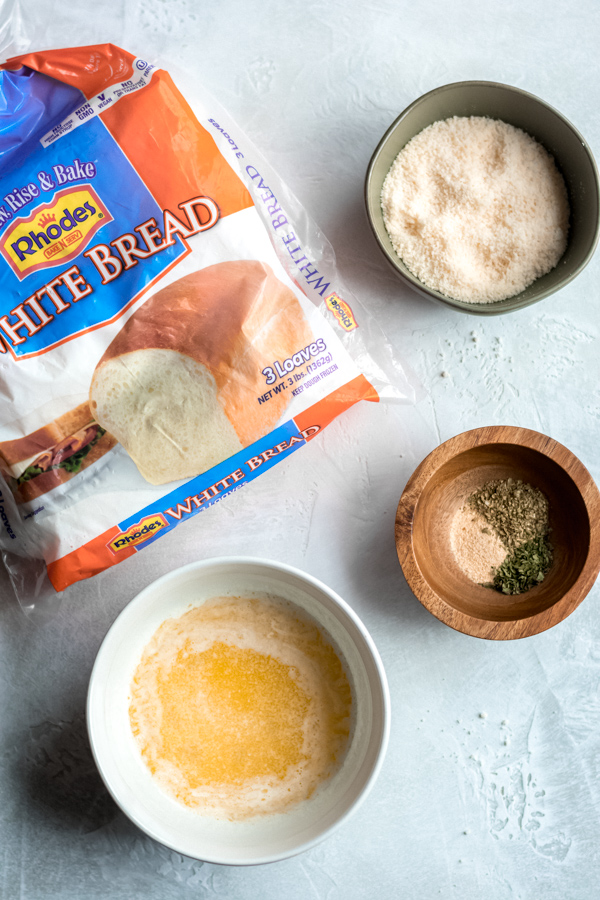 Bowls of melted butter, garlic, parmesan, and a package of white bread.