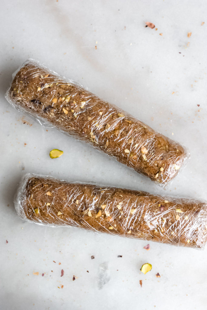 Cookie dough rolls wrapped in plastic wrap.