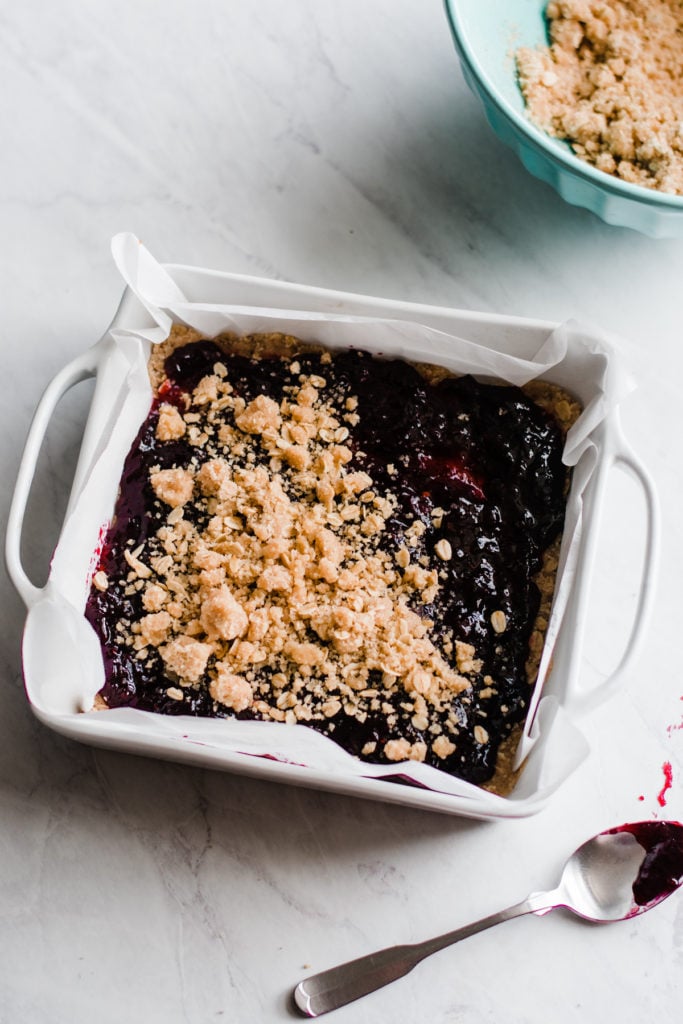 Crumble topping on blackberry jam in a pan.