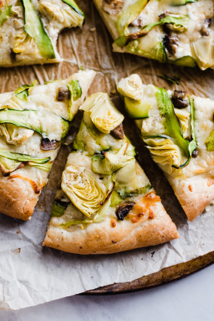 Green Goddess Pizza - It may sound completely unusual but I promise it tastes like Spinach Artichoke Dip in pizza form. Made with zucchini ribbons, garlicky sautéed mushrooms (trust!), artichoke hearts, olive oil, and plenty of mozzarella and parmesan cheese - all on a crust made from Rhodes pre-made dough. #pizza #artichoke #zucchini #vegetarian #veganpizza #vegetarianpizza #mushroom #easydinner #pizzanight #movienightrecipes #bluebowlrecipes #ad | bluebowlrecipes.com