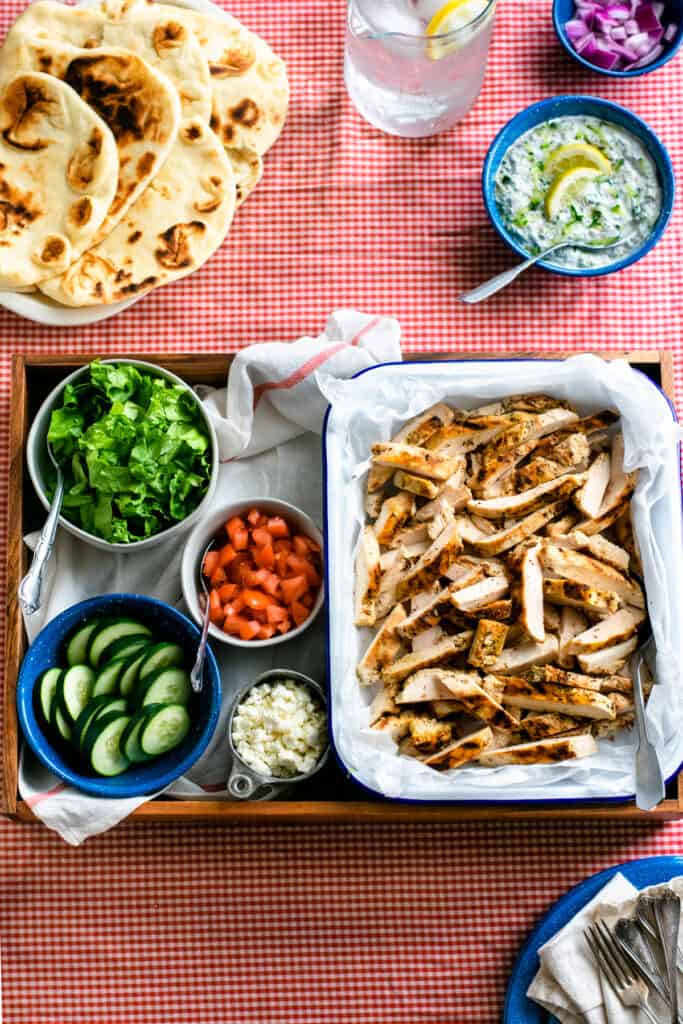 Grilled chicken gyro ingredients in bowls on a tray.