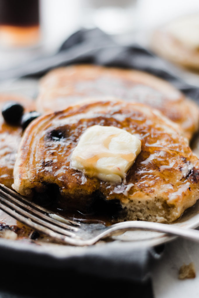 Close-up of a blueberry pancake with butter and syrup.