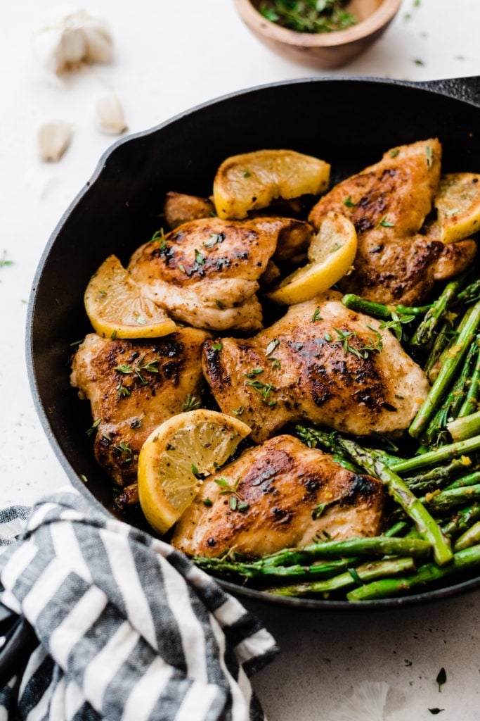 Lemon garlic chicken and asparagus in a cast iron skillet.