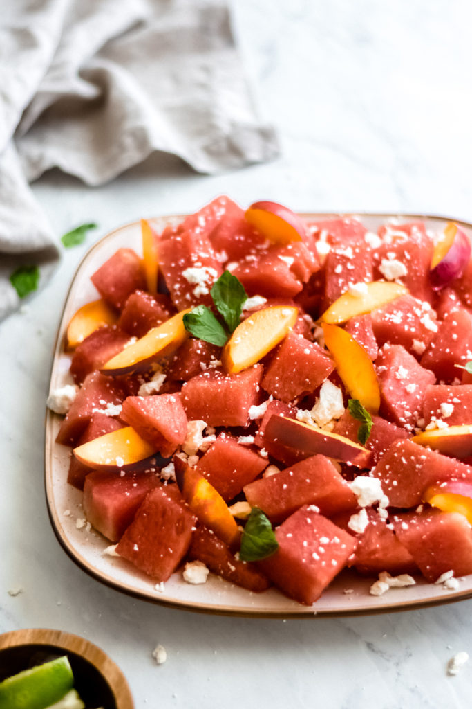 Watermelon nectarine salad with feta and honey lime dressing on a plate.