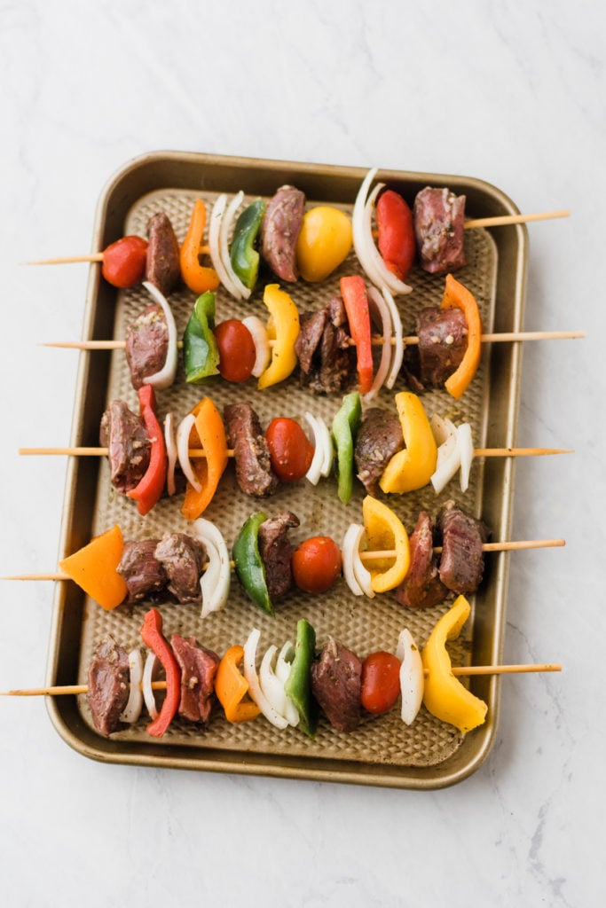 Lamb kebabs assembled on skewers on a tray.