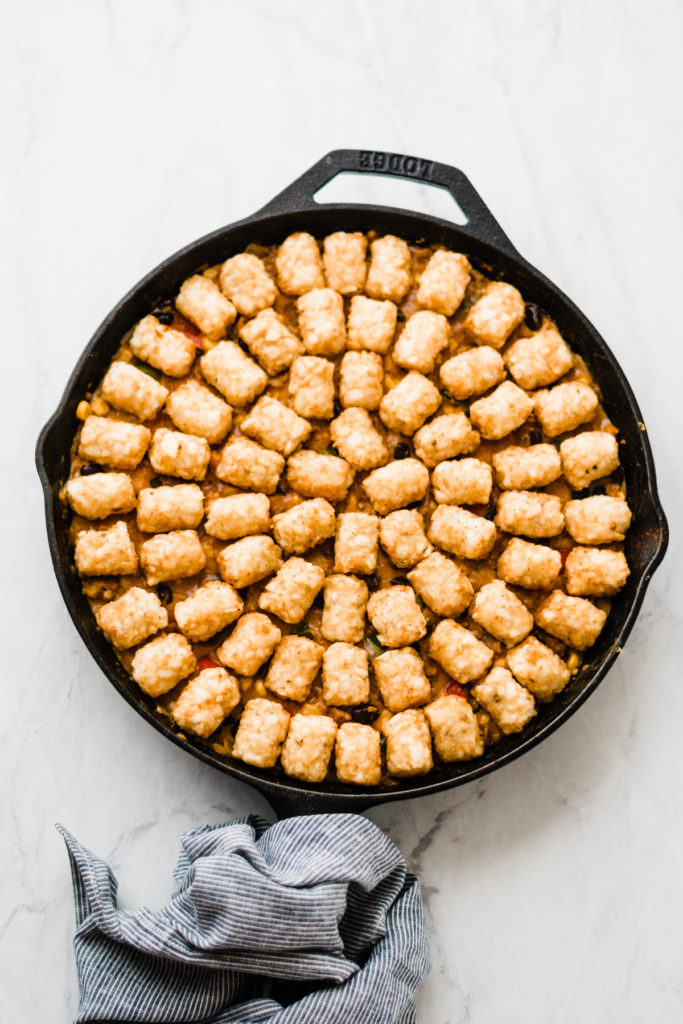 Tater tots placed into skillet over filling.