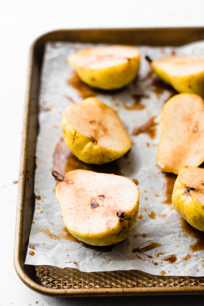Halved pears on a baking sheet.