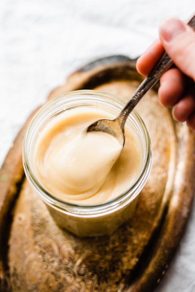 A spoon digging into a jar of maple glaze.
