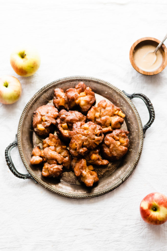 Homemade Apple Fritters w/ Buttery Maple Glaze - If you haven't had a good Apple Fritter yet, you are missing out. These are surprisingly simple to make and they are OUT OF THIS WORLD delicious! Light and fluffy on the inside, crisp on the outside, drenched in buttery maple glaze - they practically melt in your mouth. #applefritters #dessert #baking #falldessert #fallbaking #donuts #halloweenrecipes #thanksgivingrecipes #holidayrecipes #holidaydessert #ad #bluebowlrecipes | bluebowlrecipes.com