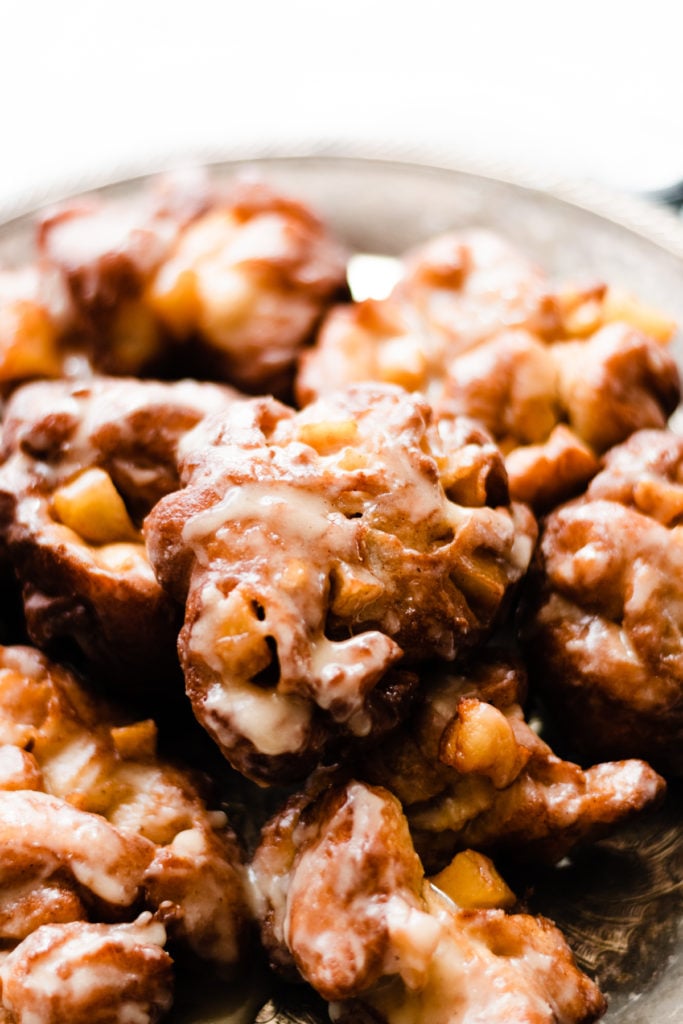 Homemade Apple Fritters w/ Buttery Maple Glaze - If you haven't had a good Apple Fritter yet, you are missing out. These are surprisingly simple to make and they are OUT OF THIS WORLD delicious! Light and fluffy on the inside, crisp on the outside, drenched in buttery maple glaze - they practically melt in your mouth. #applefritters #dessert #baking #falldessert #fallbaking #donuts #halloweenrecipes #thanksgivingrecipes #holidayrecipes #holidaydessert #ad #bluebowlrecipes | bluebowlrecipes.com