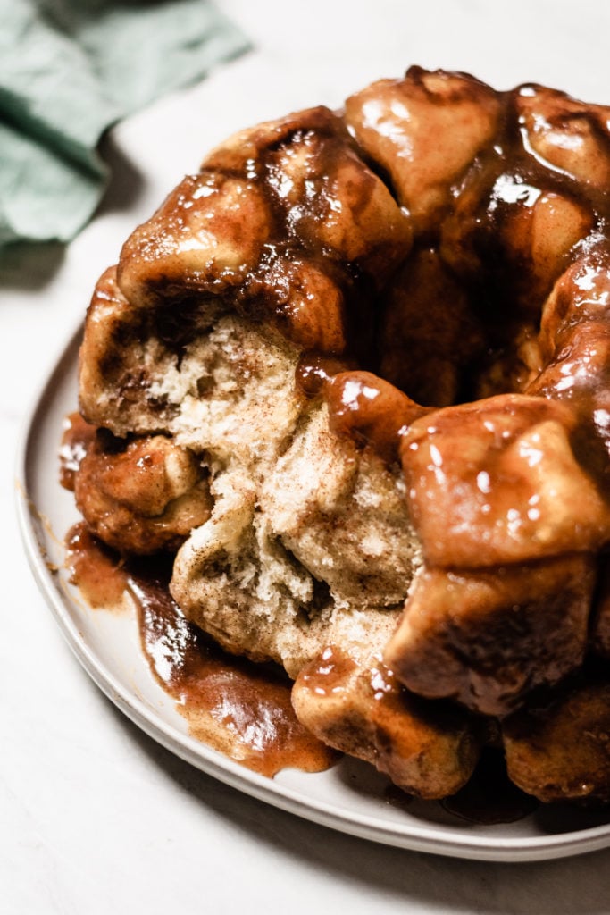 Easy Caramel Apple Cider Monkey Bread - Meet your new favorite fall treat! This Monkey Bread is light and fluffy, super flavorful, & doused in apple cider caramel sauce. This recipe comes together in no time thanks to a little help from pre-made dough. Perfect for brunch, fall gatherings, holiday parties, & game day! #halloweenfood #christmasrecipes #caramel #monkeybread #brunchrecipes #dessertrecipes #dessertideas #dessertfoodrecipes #thanksgivingrecipes #bluebowlrecipes | bluebowlrecipes.com
