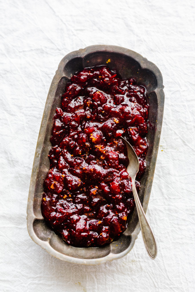 A serving dish of cranberry sauce on a white tablecloth.