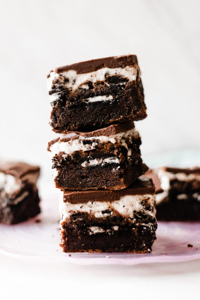 Ultimate Cookies & Cream Bars - The holiday treat to end all holiday treats! Made with a layer of thick, fudgy brownies that have a layer of oreos in the middle, & topped with sweetened condensed milk + crushed oreos. Next up, a layer of oreo frosting and a layer of chocolate to top it all off! This is the stuff of chocolate dreams! #dessertrecipes #christmascookies #brownies #oreo #christmasbaking #christmasrecipes #cookierecipes #frosting #chocolate #bluebowlrecipes | bluebowlrecipes.com