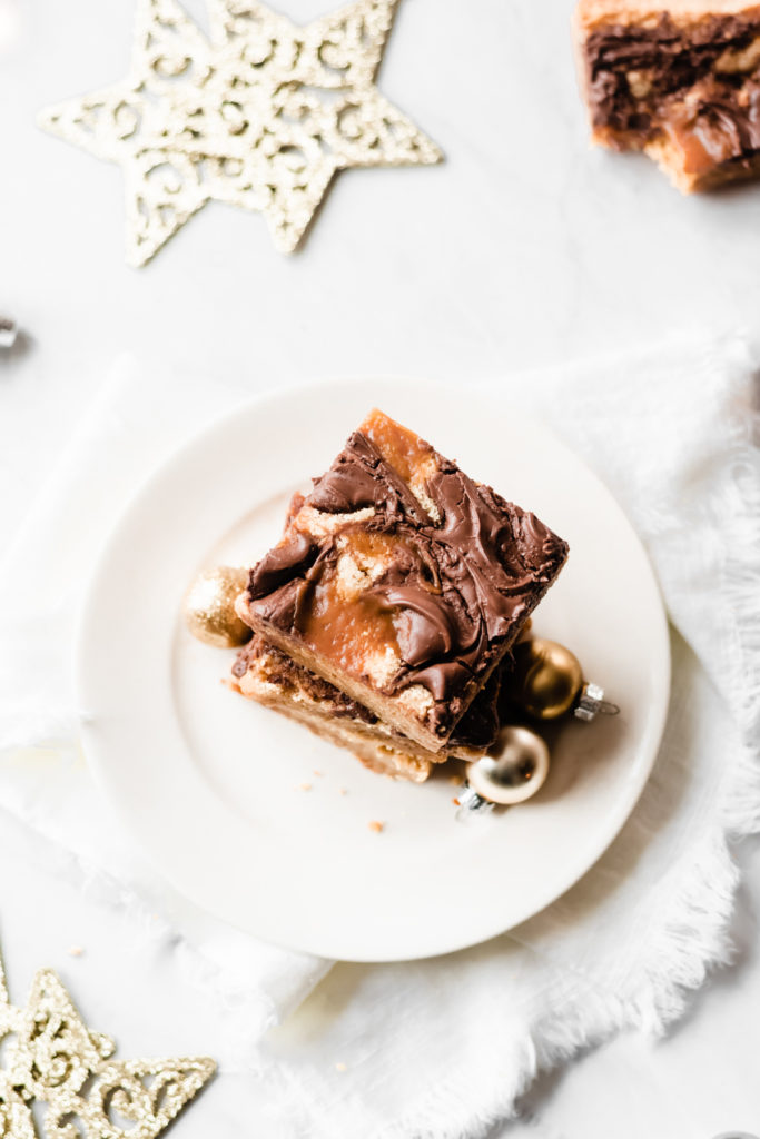 Nutella Caramel Swirled Blondies - Nutella Caramel Swirled Blondies are as beautiful to look at as they are delicious! They're made in one bowl - no mixer required - and they're buttery, gooey, and loaded with swirls of salted caramel sauce and creamy, rich nutella! These blondies absolutely deserve a place on your holiday baking list! #holidaybaking #christmascookies #blondies #caramel #nutella #dessertrecipes #christmasrecipes #christmascookies #bluebowlrecipes | bluebowlrecipes.com