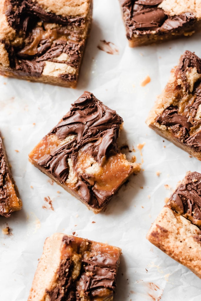 Nutella Caramel Swirled Blondies - Nutella Caramel Swirled Blondies are as beautiful to look at as they are delicious! They're made in one bowl - no mixer required - and they're buttery, gooey, and loaded with swirls of salted caramel sauce and creamy, rich nutella! These blondies absolutely deserve a place on your holiday baking list! #holidaybaking #christmascookies #blondies #caramel #nutella #dessertrecipes #christmasrecipes #christmascookies #bluebowlrecipes | bluebowlrecipes.com
