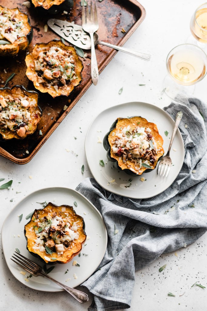 Stuffed Acorn Squash is the perfect dish for Friendsgiving & Thanksgiving! Made with oven-roasted acorn squash – complete with caramelized edges - & filled with wild rice, sweet honeycrisp apples, chopped celery, ground lamb, dried cranberries. Top the whole thing off with fresh herbs and parmesan for a dish that's as beautiful as it is delicious! #stuffedacornsquash #acornsquash #thanksgivingrecipes #thanksgivingsidedish #thanksgivingfood #friendsgiving #bluebowlrecipes | bluebowlrecipes.com