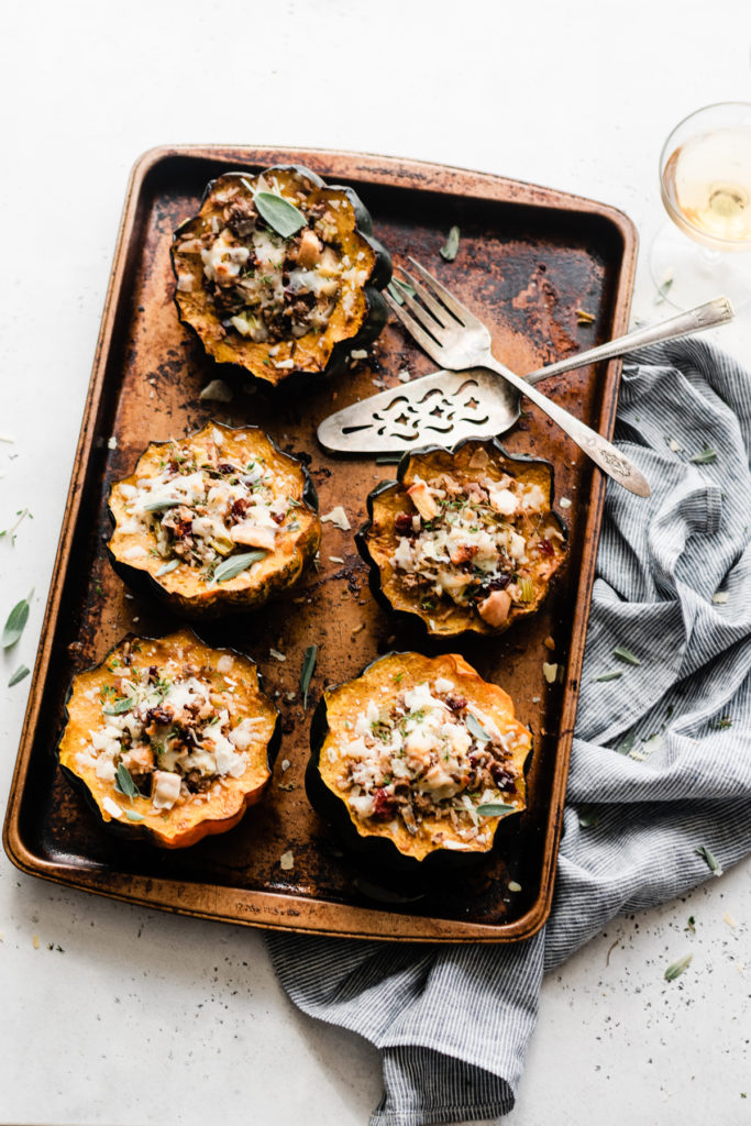 Stuffed Acorn Squash is the perfect dish for Friendsgiving & Thanksgiving! Made with oven-roasted acorn squash – complete with caramelized edges - & filled with wild rice, sweet honeycrisp apples, chopped celery, ground lamb, dried cranberries. Top the whole thing off with fresh herbs and parmesan for a dish that's as beautiful as it is delicious! #stuffedacornsquash #acornsquash #thanksgivingrecipes #thanksgivingsidedish #thanksgivingfood #friendsgiving #bluebowlrecipes | bluebowlrecipes.com