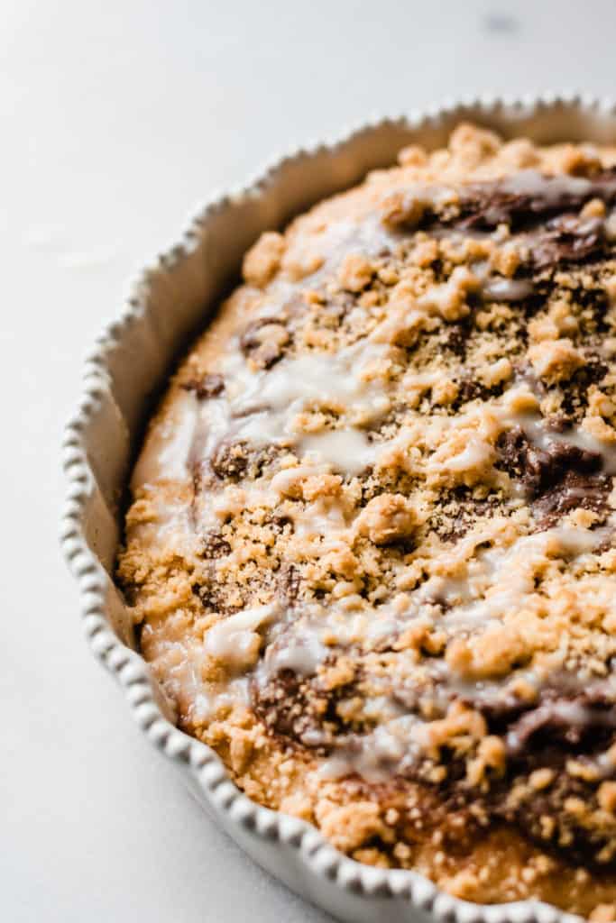 Deep Dish Nutella Dessert Pizza - Deep Dish Nutella Dessert Pizza is rich, covered in nutella and melted chocolate, and topped with a buttery streusel. Drizzle a white chocolate glaze on top and dive in to dessert heaven! #dessertrecipes #nutella #chocolate #chocolaterecipes #christmasbaking #holidayrecipes #holidaydesserts #chocolatedesserts #dessertpizza #holidaybaking #christmasdesserts #easyrecipe #easydesserts #bluebowlrecipes | bluebowlrecipes.com