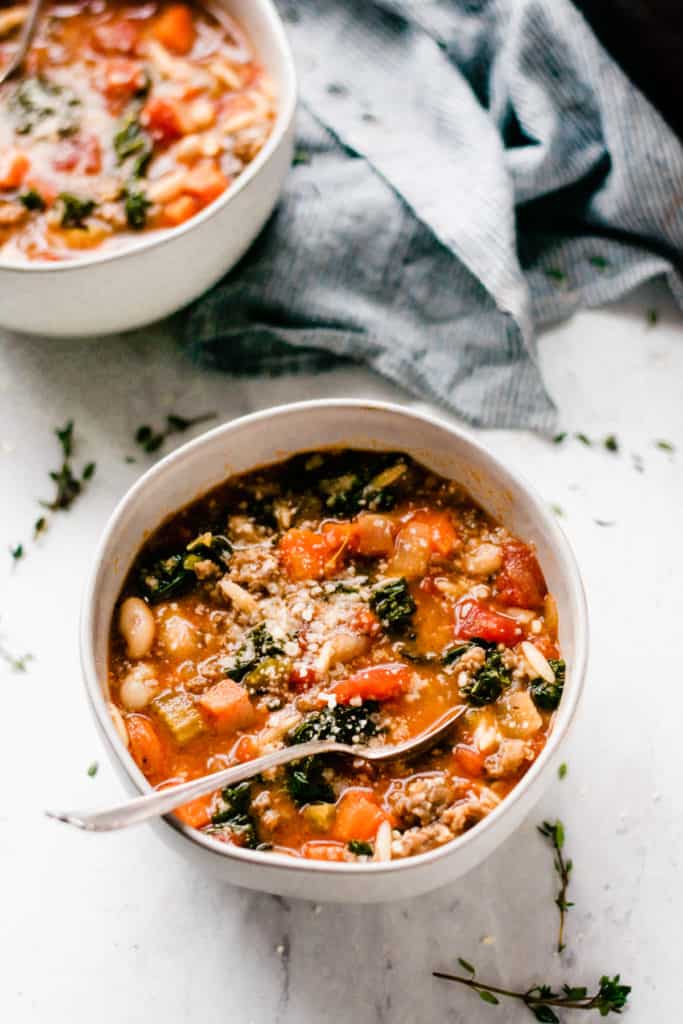 Healthy and Hearty Minestrone Soup - Made with carrots, diced tomatoes, kale, orzo, sausage, and TONS of flavor! This soup is the perfect cold-weather comfort food. It's filling, healthy, tastes incredible, and it's ready in under an hour! #soup #souprecipes #easyrecipes #glutenfreerecipes #minestronesoup #minestrone #winterrecipes #comfortfood #comfortfoodrecipes #healthyrecipes #dinnerrecipes #easyrecipes #easydinner #dairyfreerecipes #bluebowlrecipes | bluebowlrecipes.com