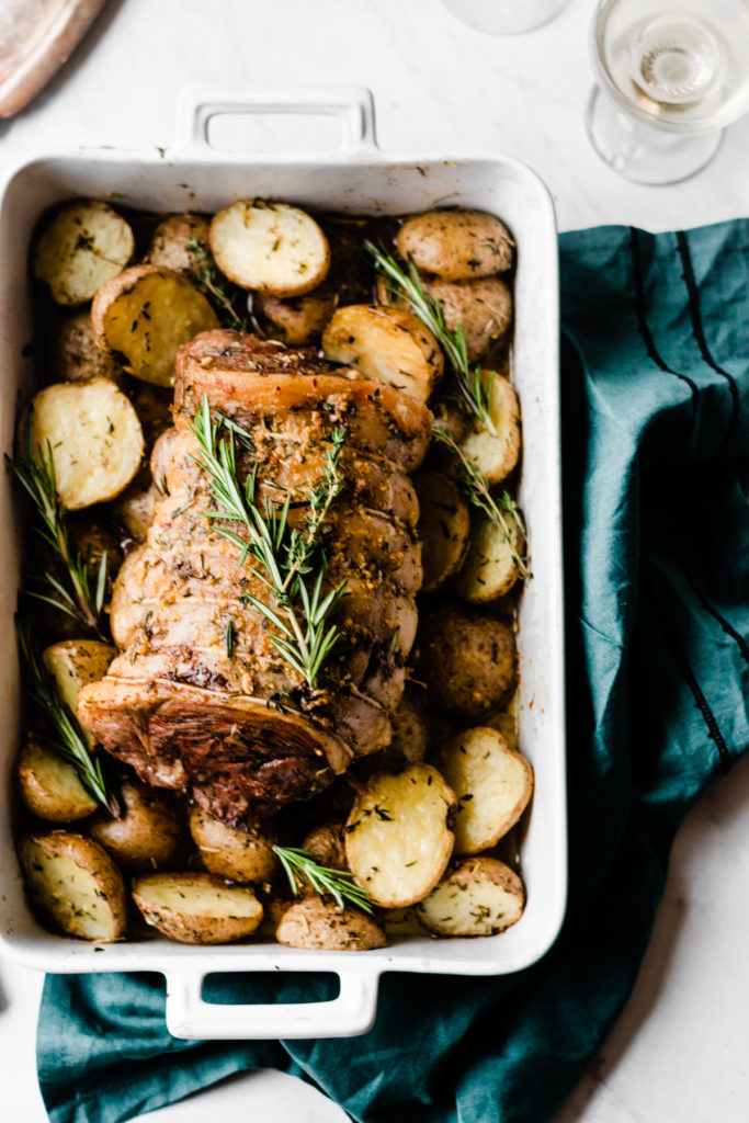 Lamb Roast with Herbed Garlic Butter Potatoes - The holiday dinner that tastes + looks fabulous, while secretly being extremely simple to make! Rub the lamb with olive oil + herbs and drench the potatoes in melted butter, garlic, and herbs and roast everything for the most flavorful dinner! #dinnerrecipes #holidayrecipes #christmasdinner #christmasrecipes #lamb #roast #glutenfreerecipes #easyrecipes #healthyrecipes #bluebowlrecipes | bluebowlrecipes.com