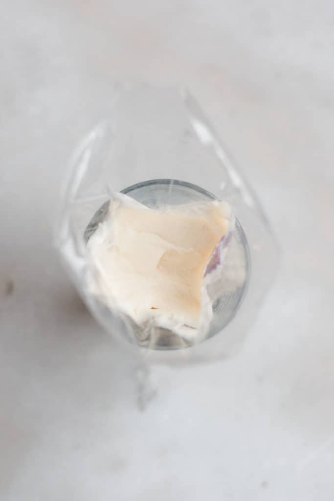 A piping bag filled with frosting, inside a drinking glass